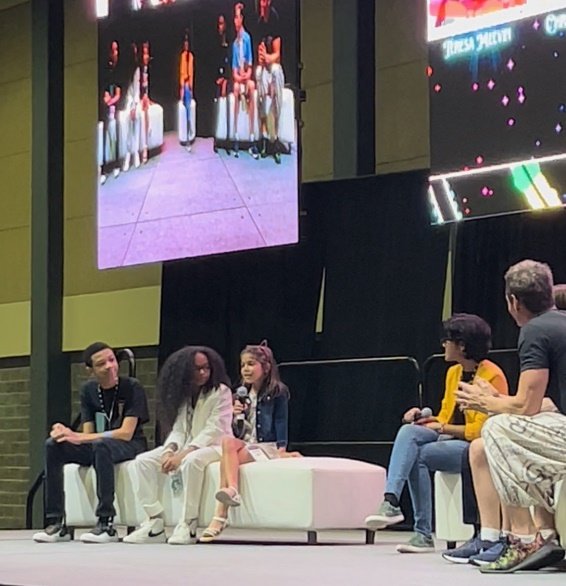 A group of people sitting on a couch watching a presentation Description automatically generated with low confidence