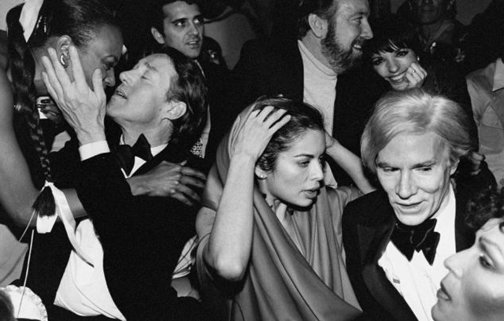 A group of people in a crowd with Studio 54 in the background Description automatically generated